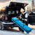 Action view of a traveler handling the blue XCMAN snowboard travel bag near a vehicle trunk, showcasing everyday convenience