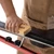 Action shot of a technician using a brush on a cross-country ski mounted securely on the XCMAN nordic waxing profile table