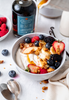 Yogurt bowl topped with fruit and maple syrup with Madagascar Vanilla Infused organic maple syrup bottle
