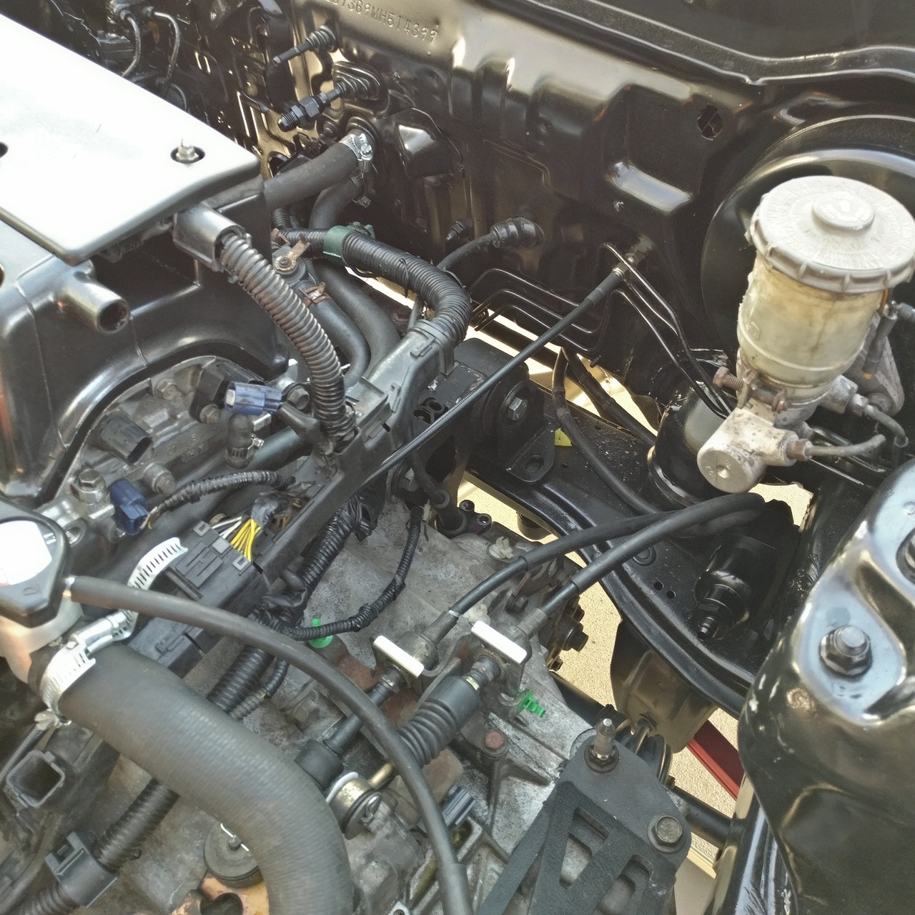 Wide engine-bay view of JBtuned K-swap hydro clutch line routing from the firewall bulkhead toward the K-Series transmission.