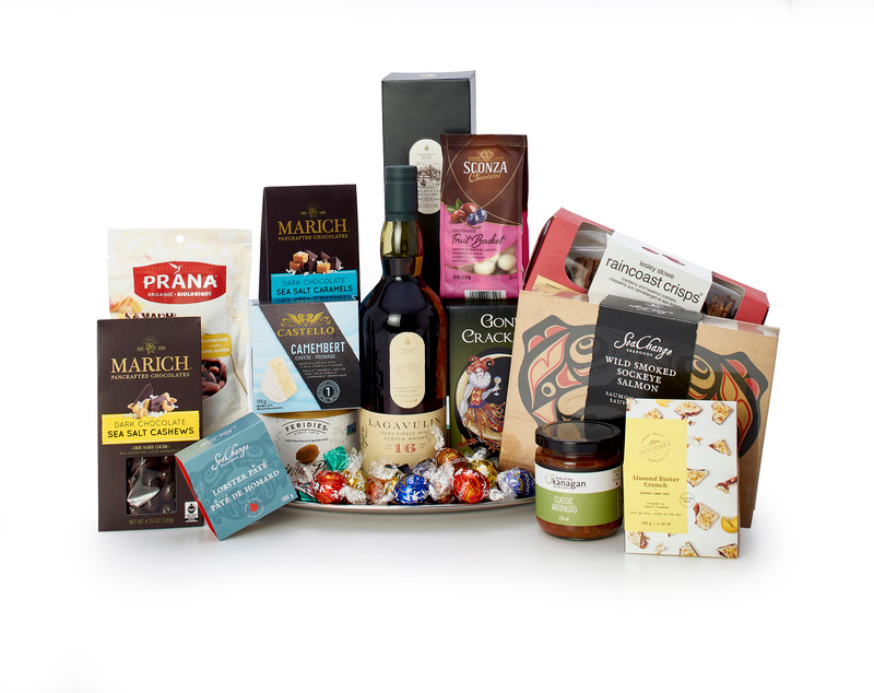 Gourmet gift basket featuring Lagavulin single malt scotch, sweet and savoury snacks (chocolate, crackers, nuts, etc.), presented on a silver tray.