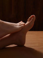 Realistic silicone sex feet posed on wood surface with lifelike toes and soft texture