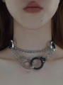 Model wearing collar with hand extended holding handcuffs