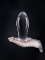 XL clear TPE anal dragon egg butt plug held upright in a gloved hand