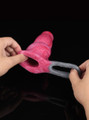 Hands stretching the hollow sleeve opening and grey ball loop of the red liquid silicone penis sleeve