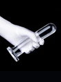 Clear flexible straight dildo held in hand with rounded tip and flared base