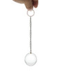 Heavy solid glass anal ball with metal chain, held between fingers.