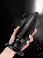 Massive black PVC butt plug in hand – perfect for extreme anal play.