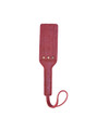 Red leather paddle placed flat, emphasizing its vivid color and premium material.