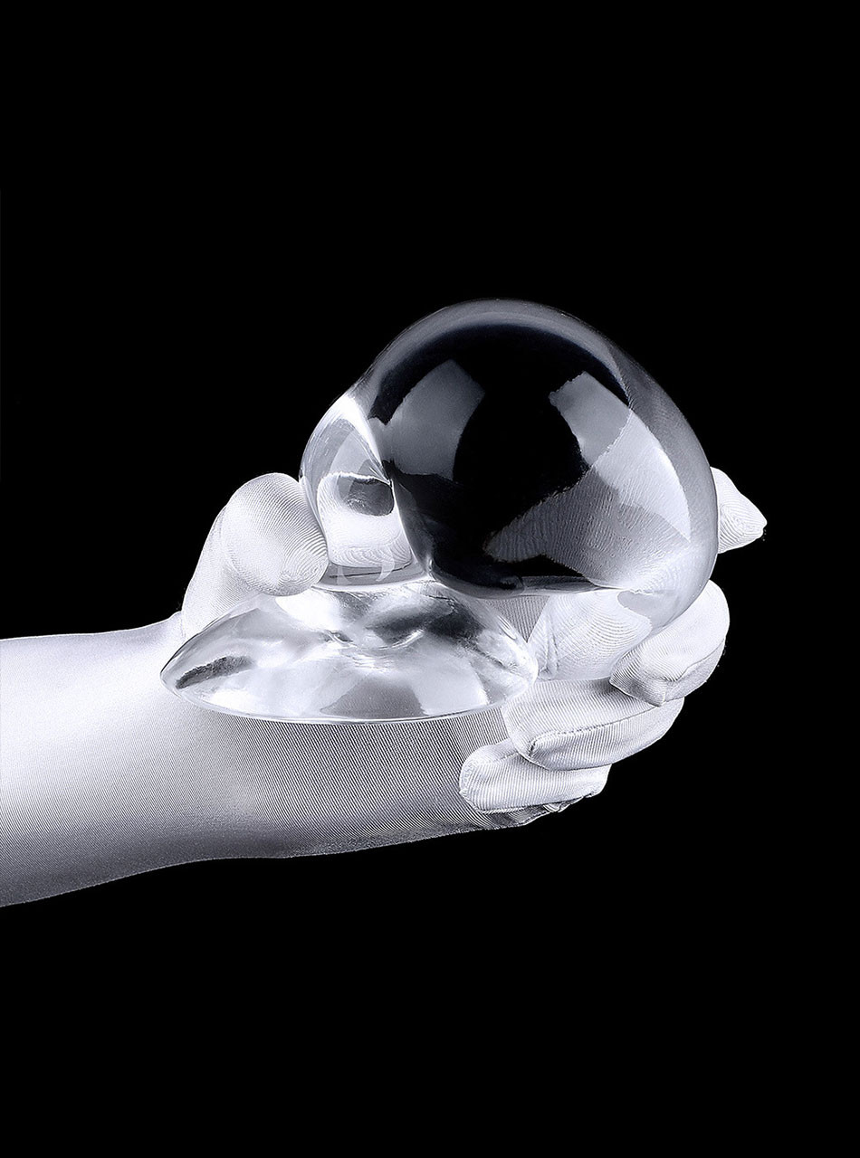 Large clear teardrop TPE plug held in a gloved hand showing wide flared base.