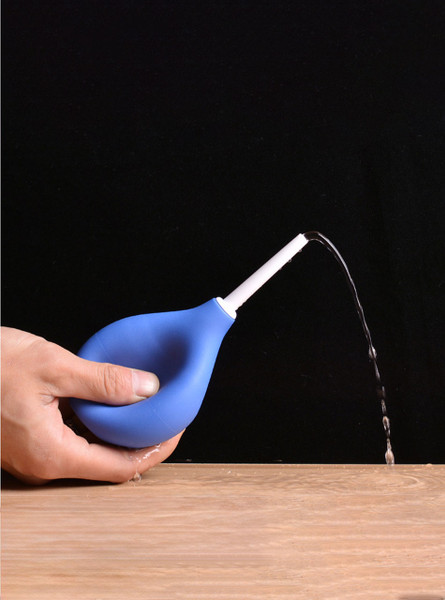 Close-up of a hand squeezing the blue douche ball, releasing water for cleansing.