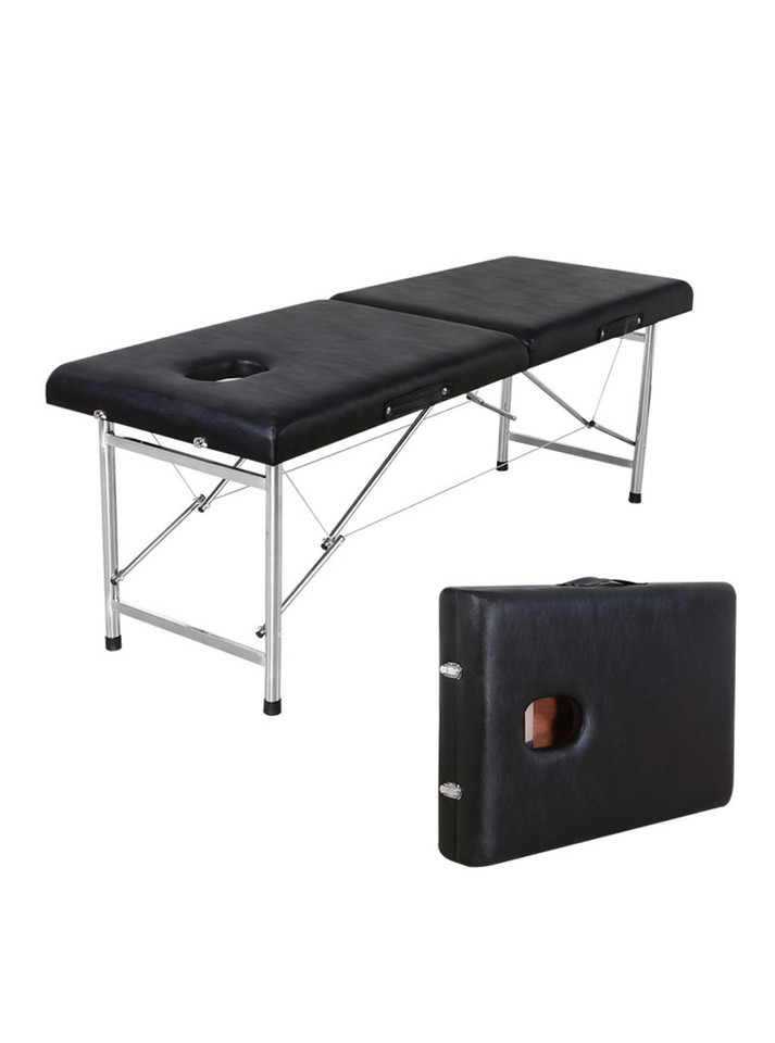 Black erotic massage table unfolded, with stainless steel legs and integrated face hole visible.