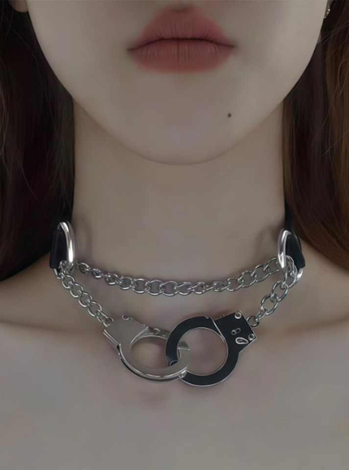 Model wearing collar with hand extended holding handcuffs