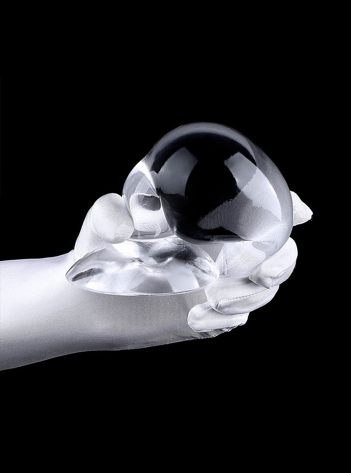 Large clear teardrop TPE plug held in a gloved hand showing wide flared base.
