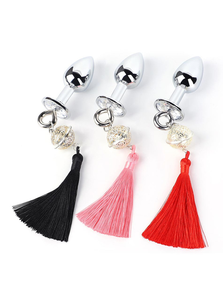 Three metal butt plugs with black, pink, and red tassels and decorative bells on white background