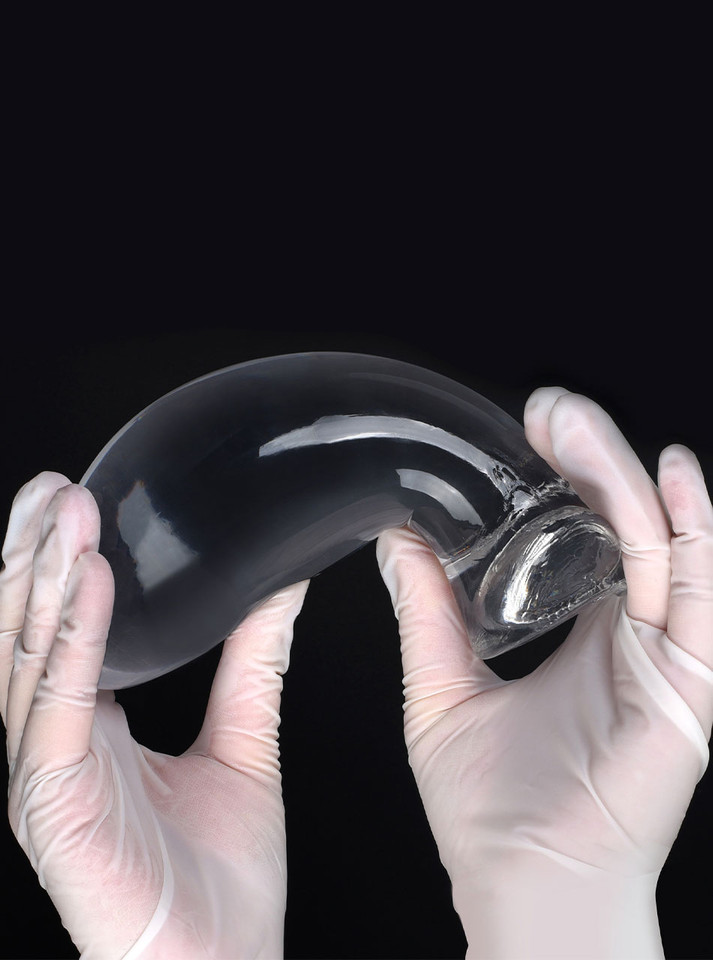Large clear TPE anal dragon egg butt plug bent between gloved hands