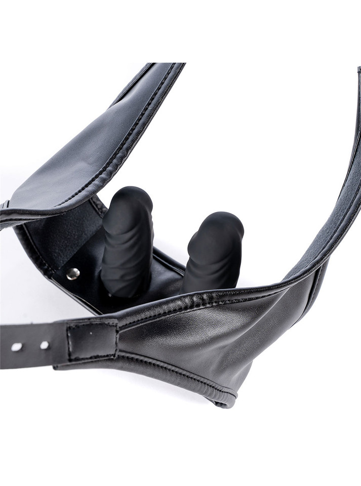 Close-up of two black silicone dildos concealed beneath the faux leather front panel of the thong.