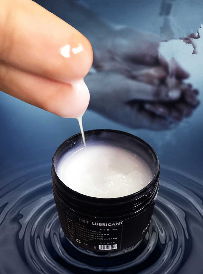 Thick white fisting lubricant gel dripping from fingers into open jar