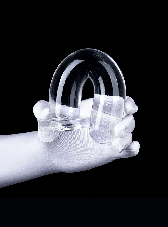 Clear flexible straight dildo bent into a U shape to demonstrate flexibility