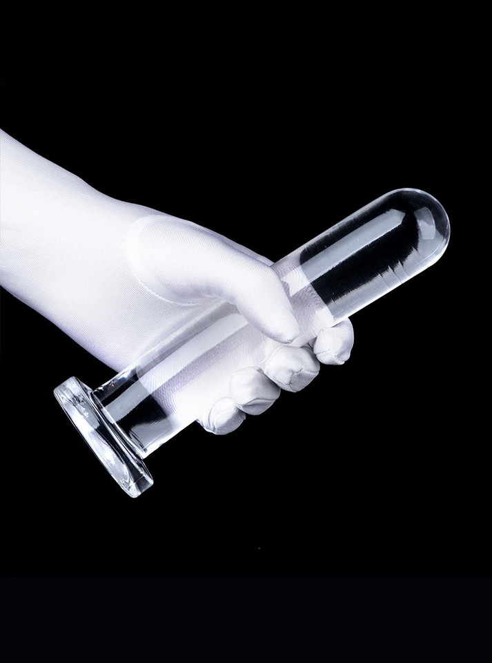 Clear flexible straight dildo held in hand with rounded tip and flared base