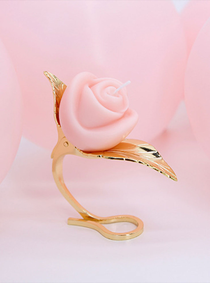 Elegant rose-shaped low-temperature candle perched on a golden leaf-designed holder.