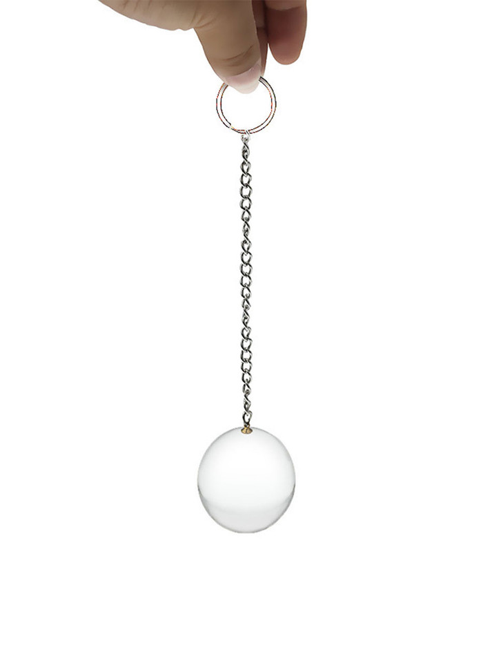 Heavy solid glass anal ball with metal chain, held between fingers.