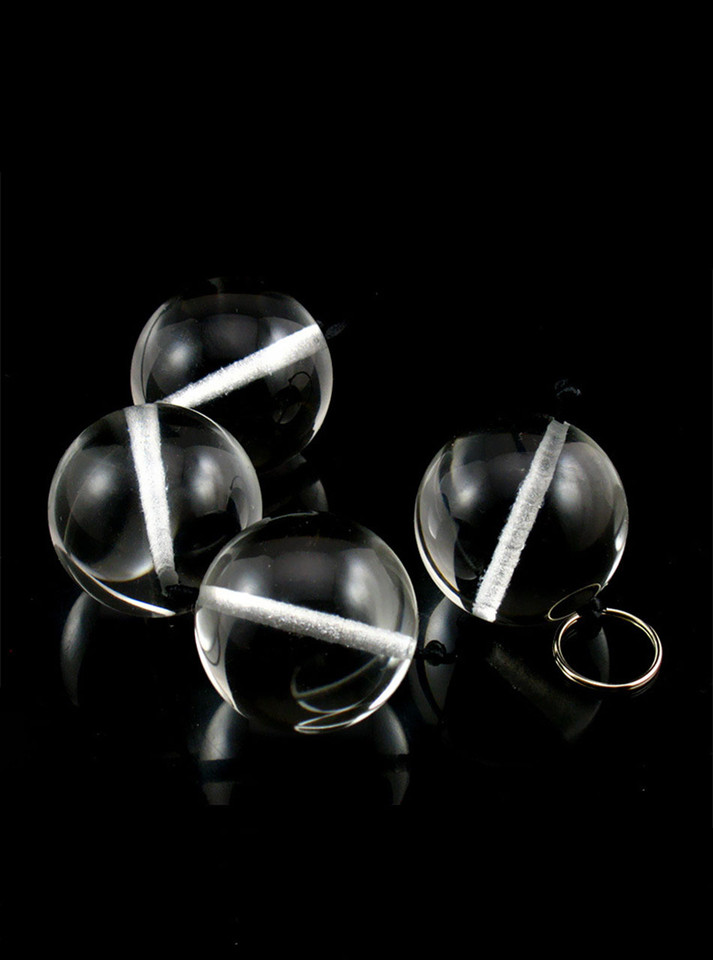 Set of crystal-clear glass anal beads with a black cord and metal ring, displayed on a sleek black background.