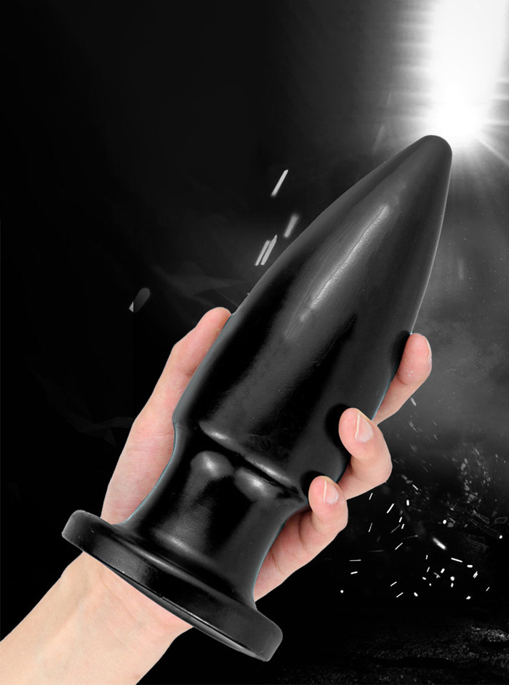Massive black PVC butt plug in hand – perfect for extreme anal play.