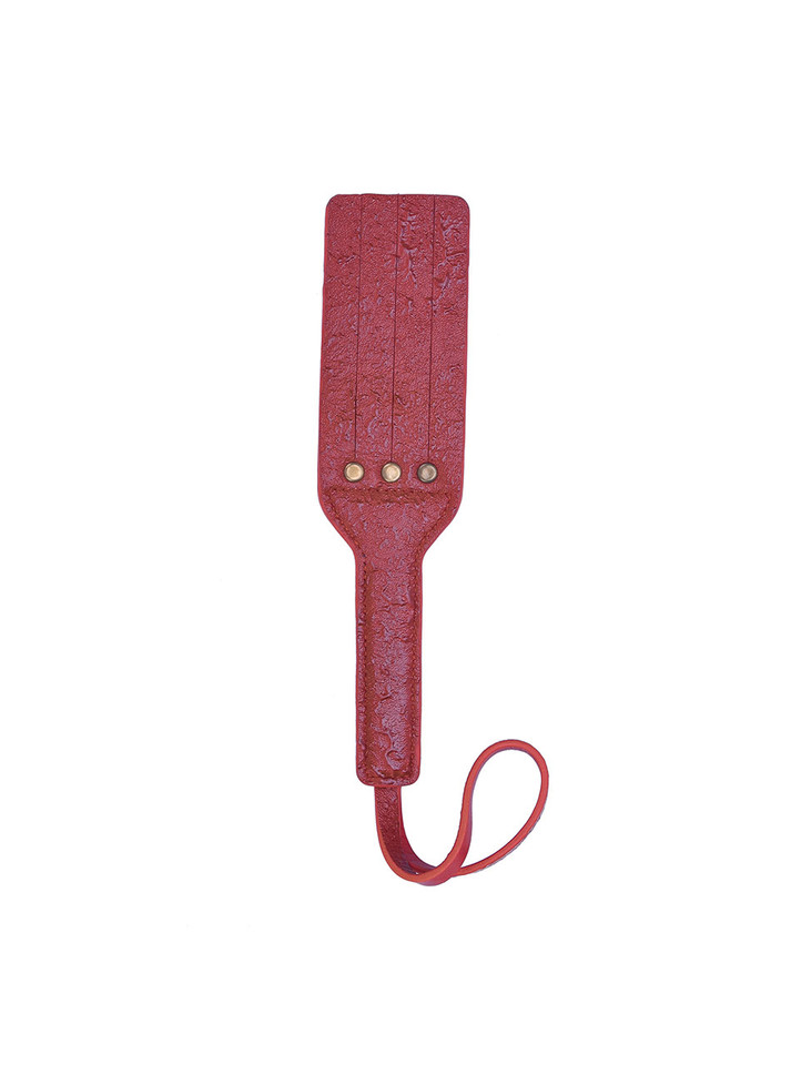 Red leather paddle placed flat, emphasizing its vivid color and premium material.