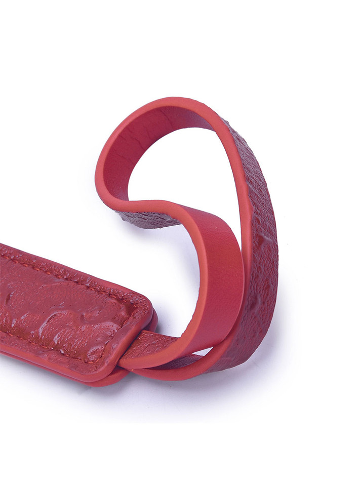 Red BDSM paddle showcasing the durable handle and bold leather design.