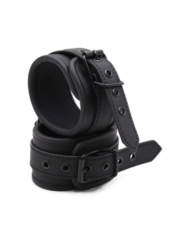 Stacked view of black sponge-lined leather bondage cuffs with sturdy black buckles and rings