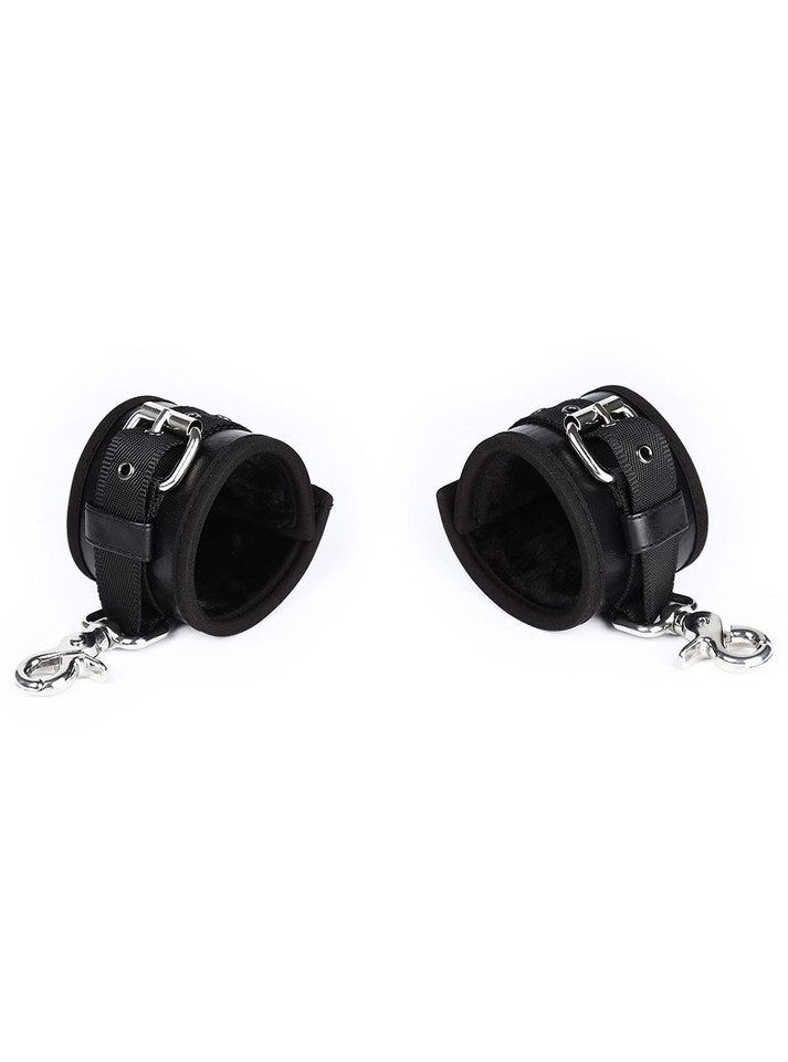Set of plush-lined black leather handcuffs laid open, showing interior padding