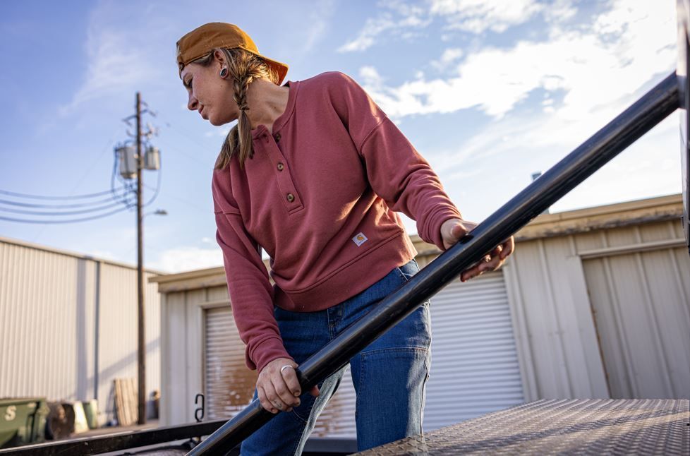 Woman in a red henley lifting pipe