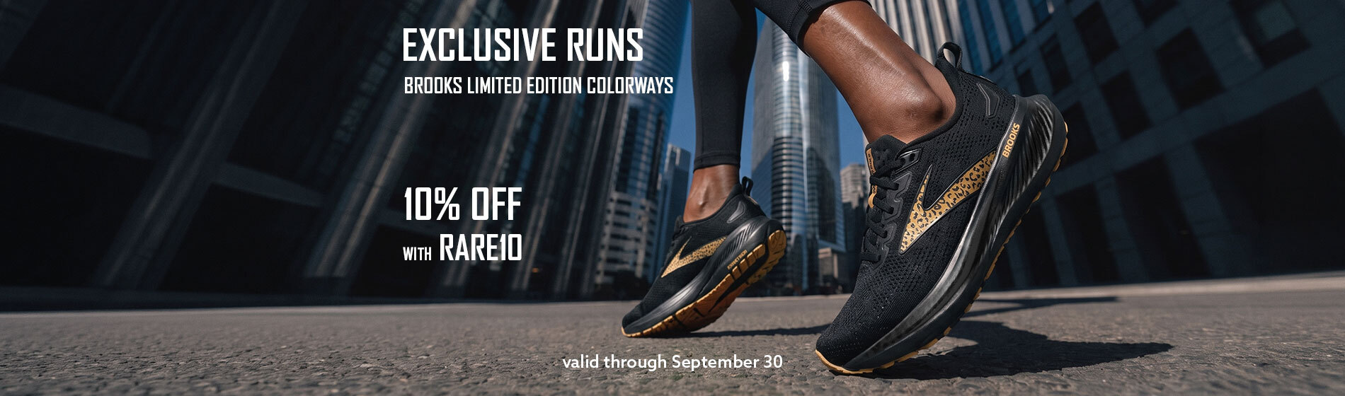 Graphic, close‑up of runner wearing black Brooks shoes with gold and leopard‑patterned limited‑edition design on city street among tall skyscrapers, text, EXCLUSIVE RUNS: Save 10% OFF on BROOKS Limited Edition Colorways — use code RARE10 at checkout