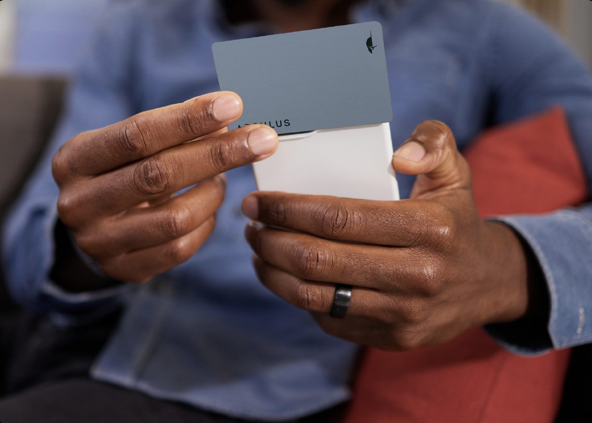 Person holding the Arculus metal card, preparing to tap it to their phone