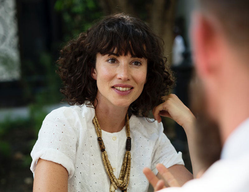 Woman wearing a white blouse paying attention to someone talking to her