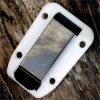 The ESEE Izula Clip Plate (ESEE-IZBC-CLR) in clear plastic, shown with its mounting screws and washers, designed to fit both Izula and Izula-II sheaths.