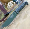 The ESEE-6 3D Handle (6POD-003) shown with its 6.50-inch 1095 plain edge drop point blade in an OD Green finish and flat grind, 3D OD Green and black G-10 handle scales with finger choil, and its injection-molded black plastic sheath.