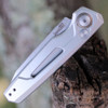Close-up of the Kershaw 7550RAW silver aluminum handle highlighting the bronze titanium pivot ring and window cutout.