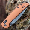 KeDetailed close-up of the DuraLock crossbar mechanism and thumb studs on the bronze Kershaw Mini Iridium.