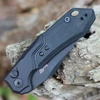 Detailed close-up of the black G-10 onlay and the bronze-anodized titanium tube spacer on the Launch 19 handle.