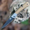 The Benchmade Successor Slipjoint (315BK-01) shown with its 2.60-inch Böhler M390 drop point blade in a black DLC finish and hollow grind, burnt brass handle scales, and its tip-up pocket clip. The nail nick opener and half-stop deployment are visible along the spine, with the black leather sheath shown alongside the knife.