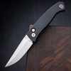Pro-Tech Brend Classic BSA26.Brend.1 shown open against a dark walnut wood background. The satin-polished 154CM clip point blade is fully deployed, extending from the solid black aluminum handle. The satin blade finish and classic Brend blade profile are clearly visible in this side profile shot.