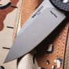 Close-up of the Pro-Tech Chaves Scapegoat Compact BSA26.Scapegoat.1 blade against the desert camouflage background, showing the stonewash MagnaMax finish and clip point geometry in detail. The Pro-Tech blade markings and stonewash surface texture are clearly visible at this focal length.