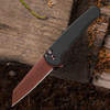 Pro-Tech Malibu BSA26.Malibu.1 shown open on a dark wood background. The copper rose PVD CPM MagnaCut reverse tanto blade is fully deployed, displaying the warm rose-toned PVD finish across the blade face. The black aluminum handle and black lip pearl button are visible at the base of the frame.