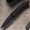 Pro-Tech TR-5 Operator T503-Operator shown open on a sandy concrete surface. The fully sterile DLC black CPM-S35VN drop point blade is deployed with no markings or engravings visible on the blade or handle. The all-black build and tritium push button are visible from this side profile angle.