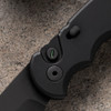 Pro-Tech TR-5 Operator T503-Operator shown closed on a sandy concrete surface, displaying the clip side of the knife. The black deep-carry tip-up pocket clip, black aluminum handle, and slide safety are visible, with the sterile no-markings build apparent from this angle.