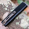Microtech UTX-85 Gen IV 12321-1JM closed — black aluminum chassis, bronze hardware, Jedi Master green blade tip visible