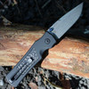 Hogue Saxum 24691-LIM open — MagnaMax stone tumbled drop point blade, matte black aluminum carbon fiber handle, Button Lock