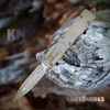 The Microtech Dirac D/E is shown with its double-edge dagger blade deployed from the front of the curved aluminum handle. The blade and handle both carry a Sand Dune Camo pattern, and the slider and pocket clip are visible.